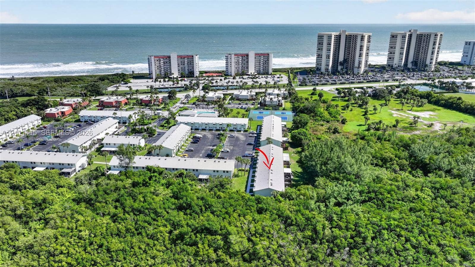 9423 S Ocean Drive, #80, Jensen Beach, FL 34957 Aerial perspective of multi-unit residential complex featuring proximity to the coastline, surface parking areas, and tennis courts