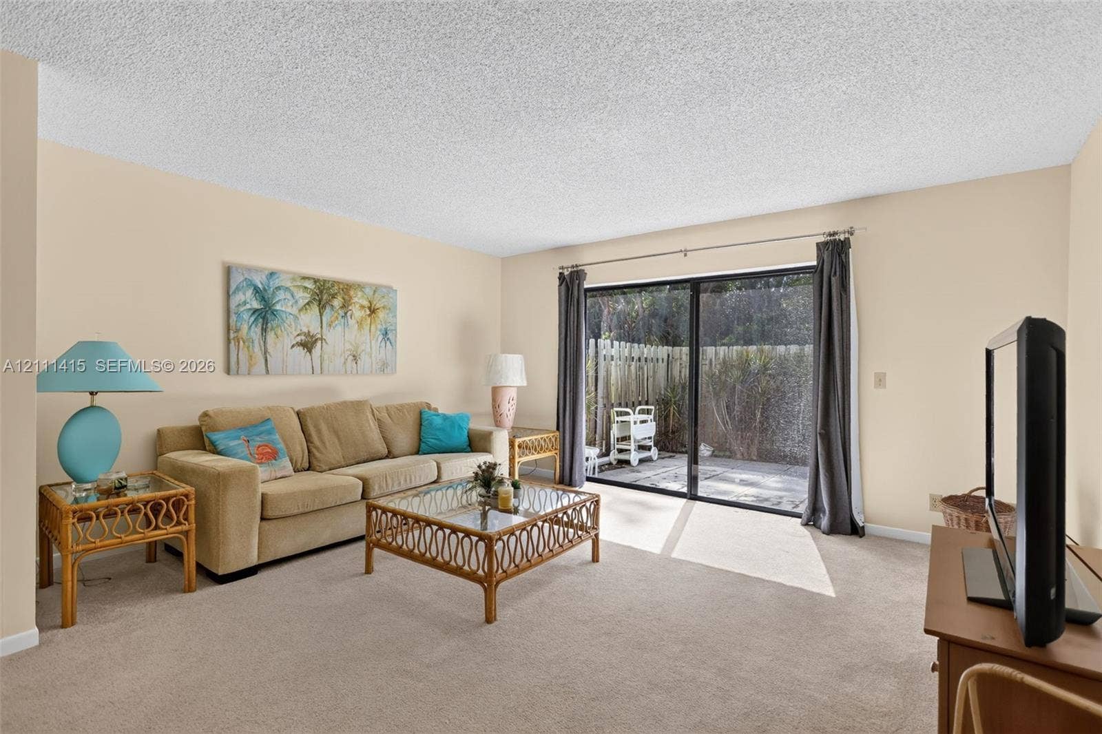 9423 S Ocean Drive, #80, Jensen Beach, FL 34957 Living area featuring neutral wall paint, textured ceiling, carpeted flooring, and a large sliding glass door providing external access