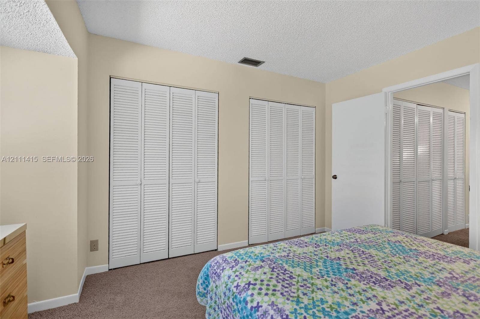 9423 S Ocean Drive, #80, Jensen Beach, FL 34957 Room featuring neutral wall tones, textile flooring, and multiple sets of white louvered-style closet doors