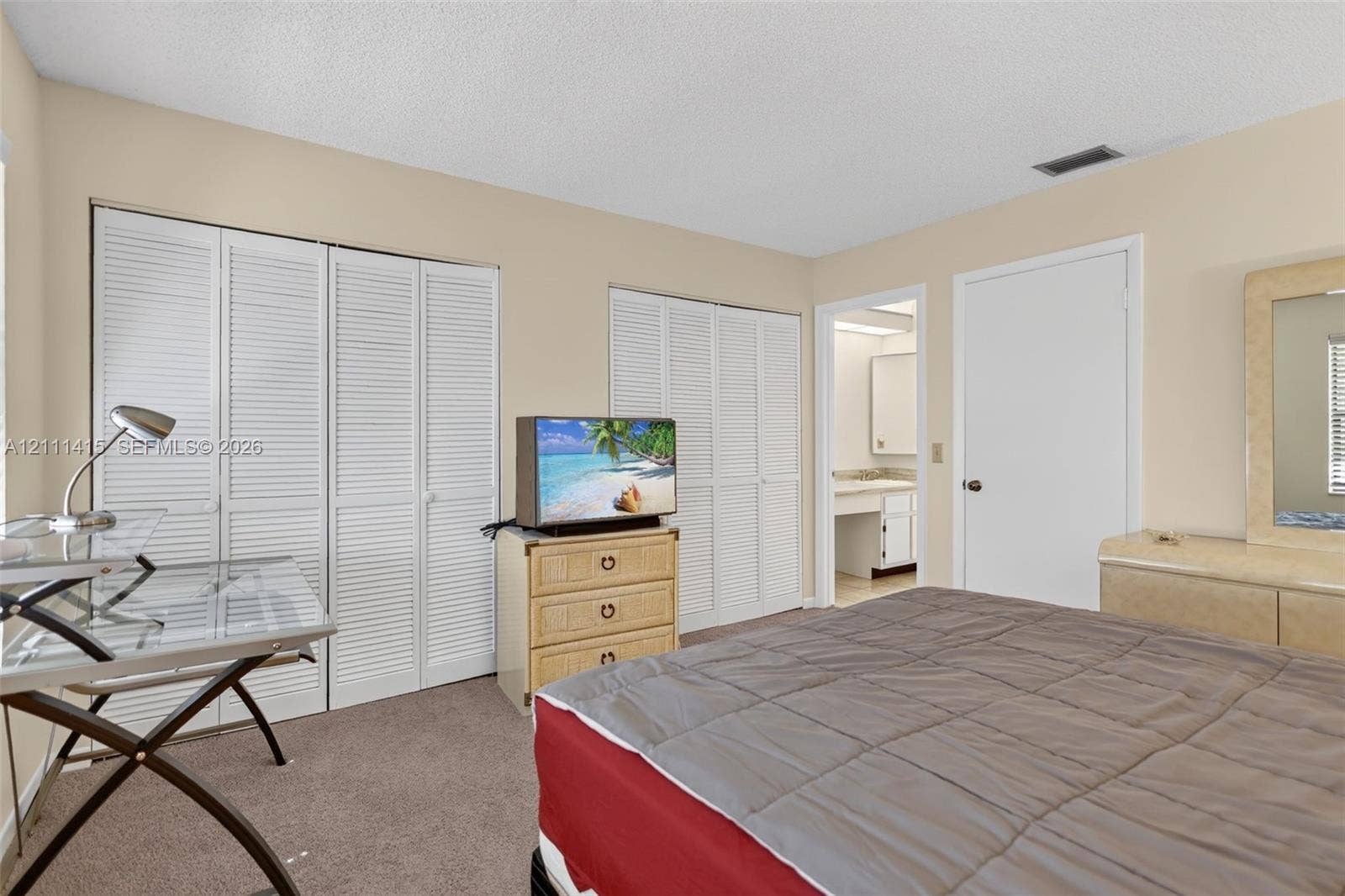 9423 S Ocean Drive, #80, Jensen Beach, FL 34957 Neutral-toned interior featuring dual sets of white louvered-door closets and wall-to-wall carpeting