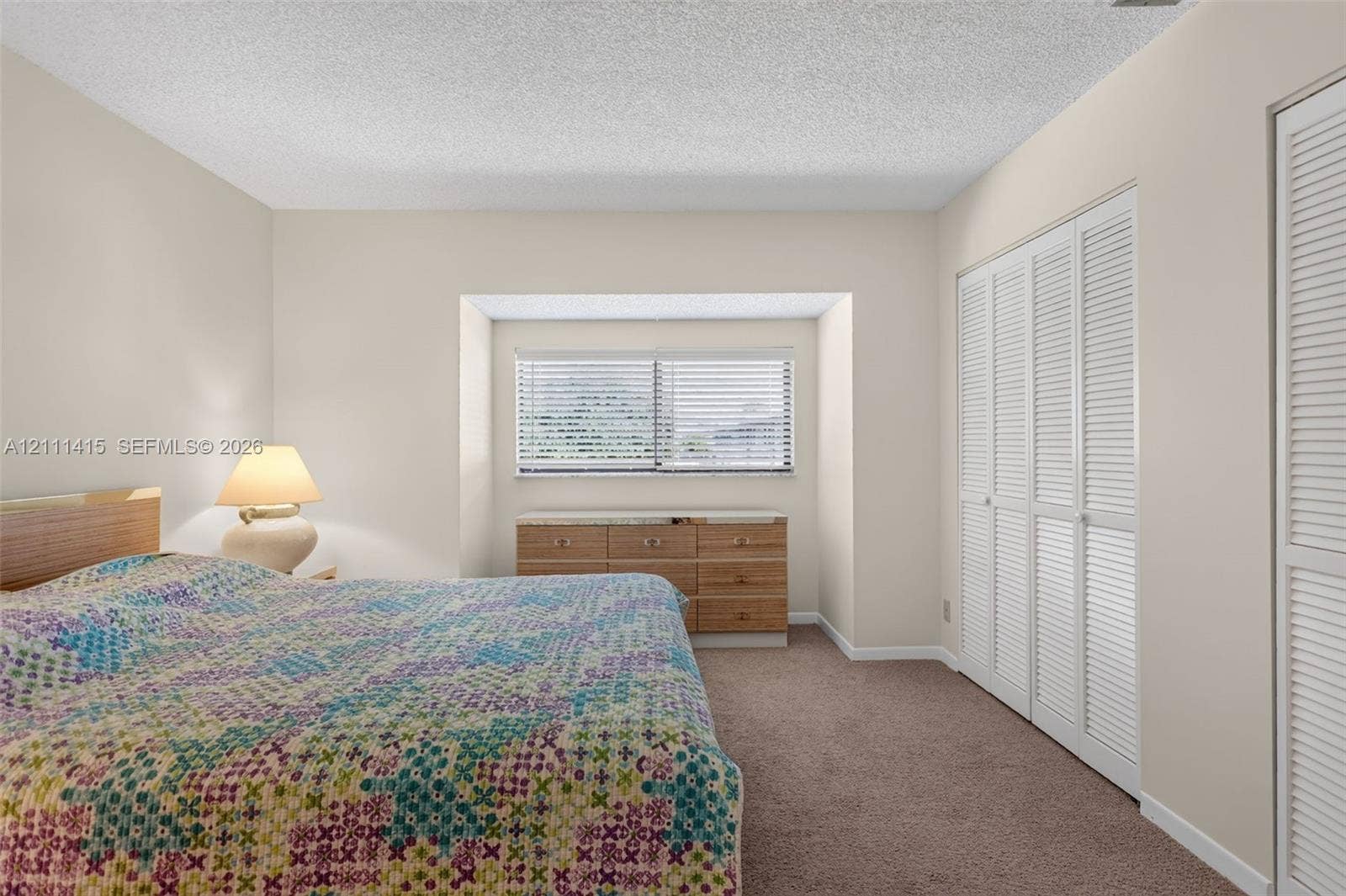 9423 S Ocean Drive, #80, Jensen Beach, FL 34957 Recessed window nook featuring a horizontal window with blinds, carpeted flooring, and floor-to-ceiling closets with louvered doors