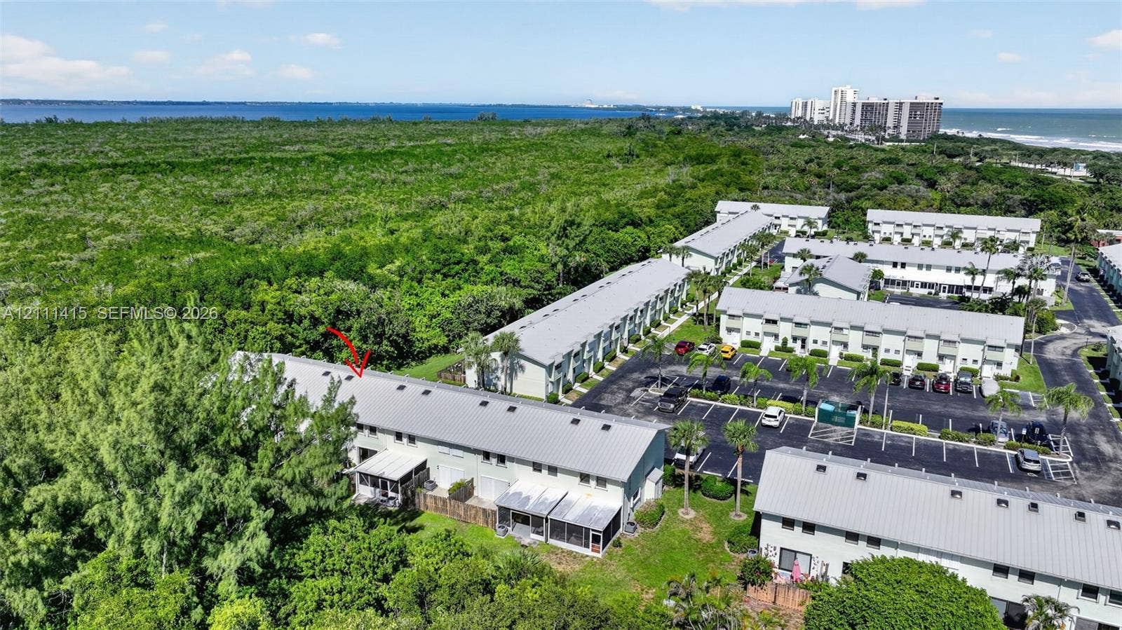9423 S Ocean Drive, #80, Jensen Beach, FL 34957 Aerial perspective of multi-unit property featuring metal roof structures, paved parking areas, and mature landscape surroundings with coastal proximity