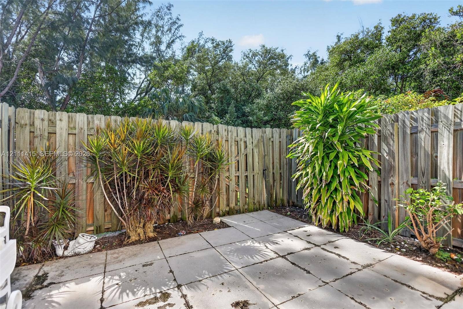 9423 S Ocean Drive, #80, Jensen Beach, FL 34957 Rear patio featuring concrete pavers, wood privacy fencing, and mature landscaping