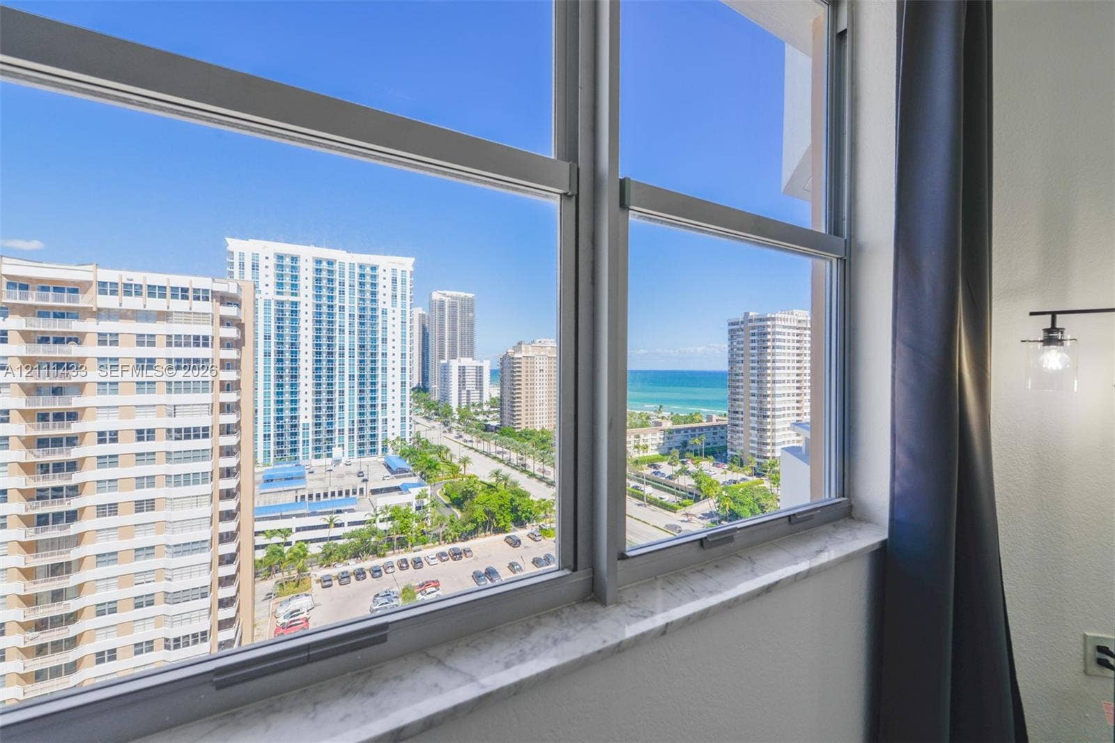 Large aluminum-framed window featuring a natural stone sill, providing an urban and coastal horizon