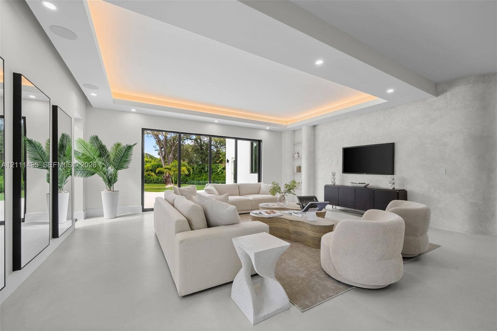 9530 SW 95th Court, Miami, FL 33176 Living area featuring a coffered ceiling with integrated cove lighting, recessed ceiling lights, a textured stone-finish accent wall, and multi-panel floor-to-ceiling glass sliding doors