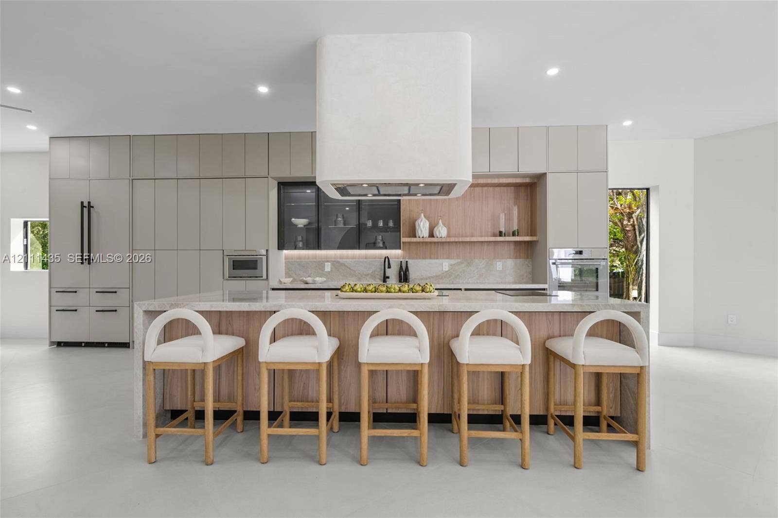 9530 SW 95th Court, Miami, FL 33176 Kitchen featuring a waterfall-edge island, custom cabinetry, integrated high-end appliances, a stone-finish backsplash, and a floating range hood