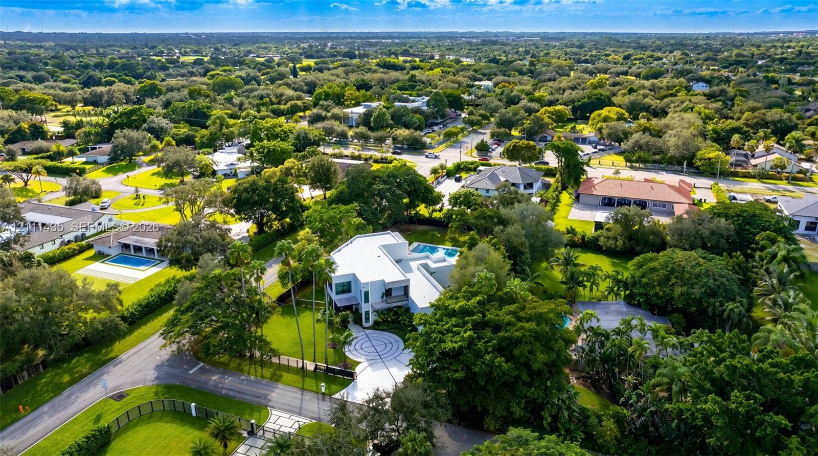 9530 SW 95th Court, Miami, FL 33176 Aerial perspective of a multi-level residence featuring a circular patterned paved motor court, expansive manicured lawn, perimeter landscaping, and a rectangular swimming pool
