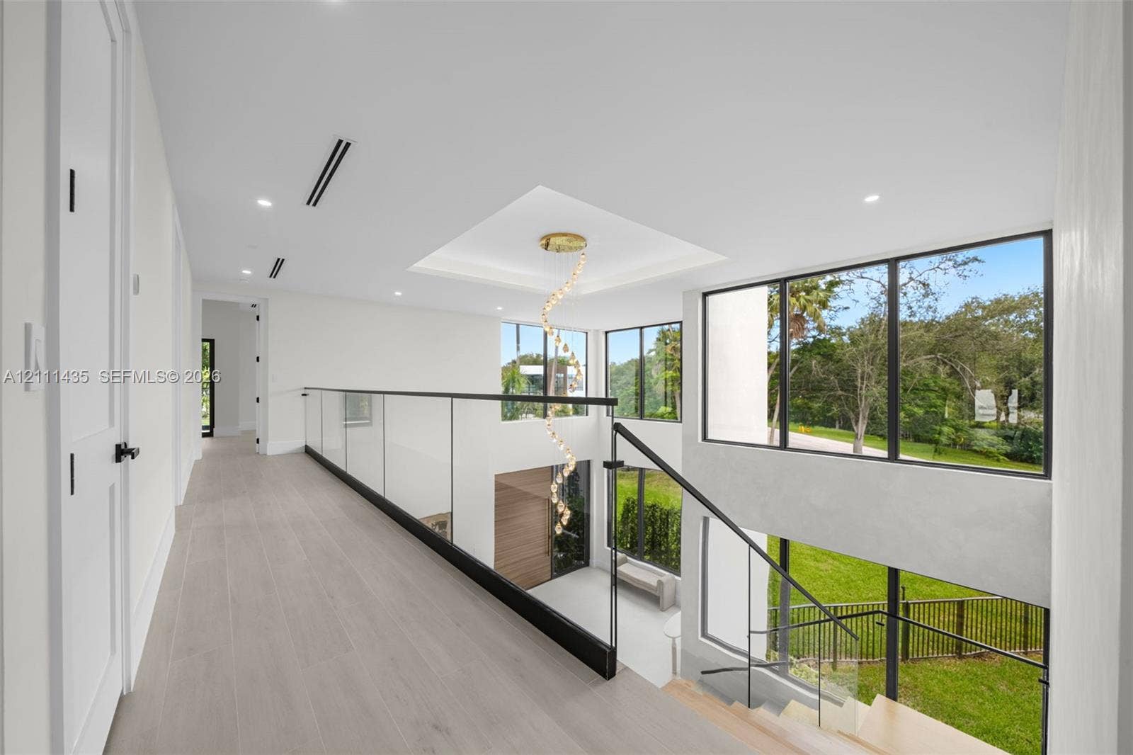 9530 SW 95th Court, Miami, FL 33176 Open landing featuring wood-finish flooring, glass panel railing with metal accents, recessed lighting, and expansive floor-to-ceiling windows