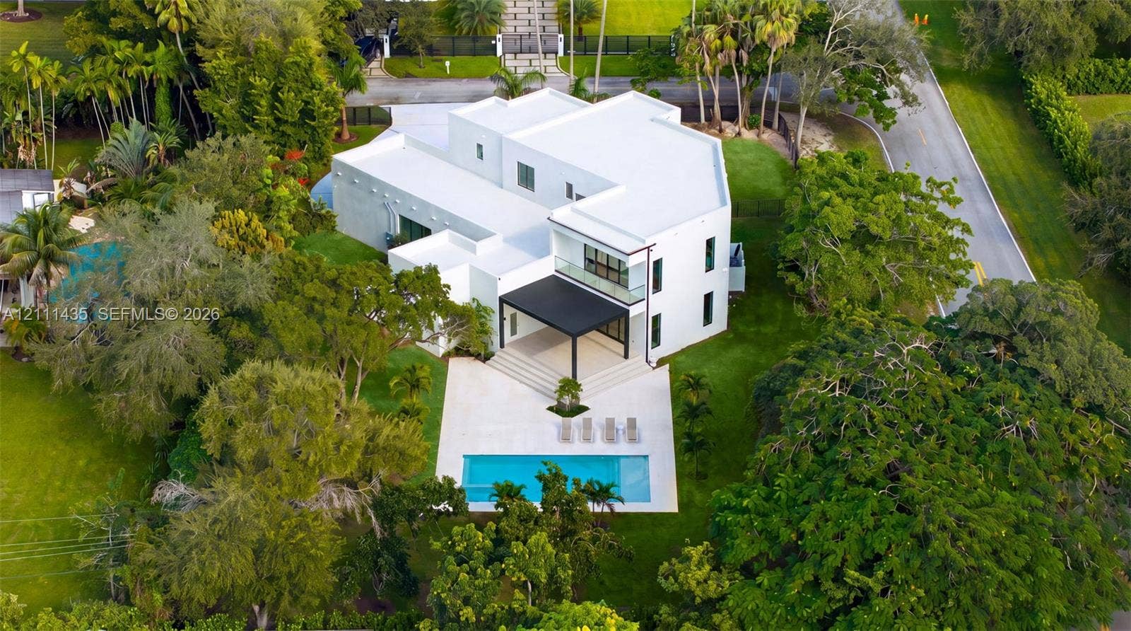 9530 SW 95th Court, Miami, FL 33176 Multi-level residence featuring a flat roofline, minimalist white exterior, covered rear terrace, private swimming pool, and stone pool deck