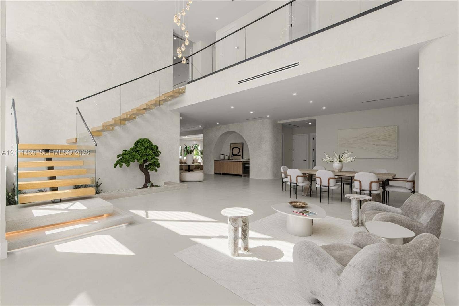 9530 SW 95th Court, Miami, FL 33176 Open-concept interior featuring a floating staircase with wood treads and glass railings, polished concrete flooring, a custom arched wall niche, and recessed ceiling lighting