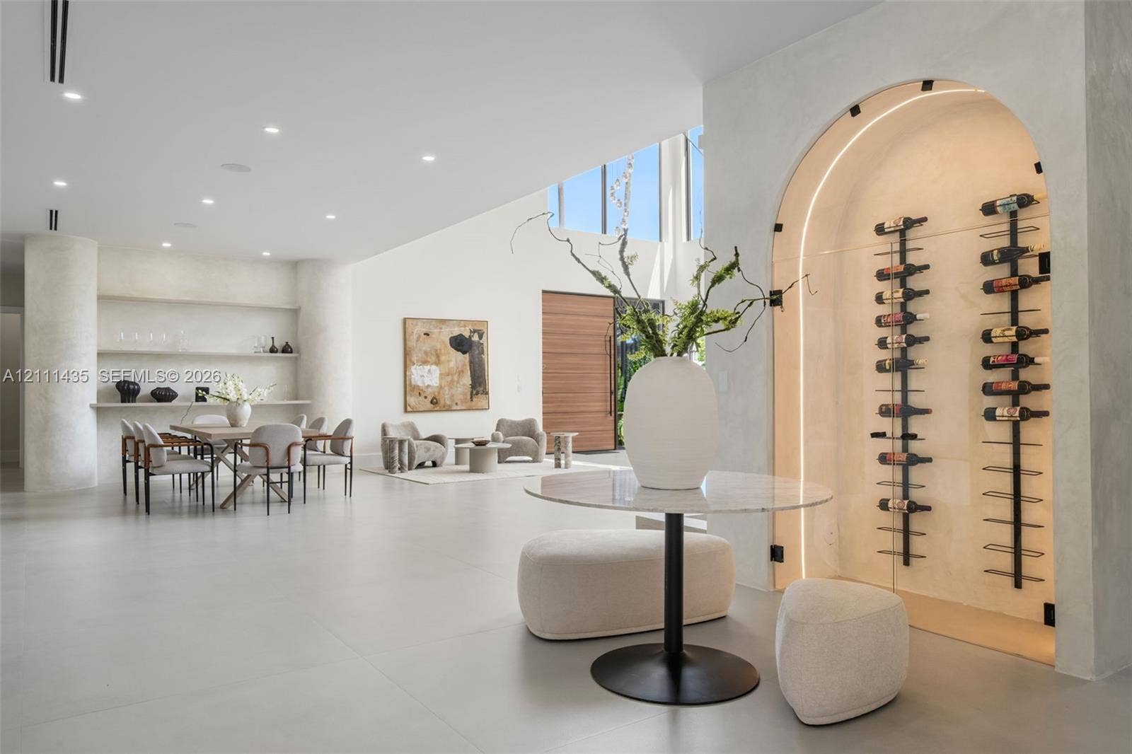 9530 SW 95th Court, Miami, FL 33176 Arched, climate-controlled glass wine display with integrated accent lighting, built-in shelving, smooth plaster wall finishes, recessed ceiling lighting, and large-format tile flooring