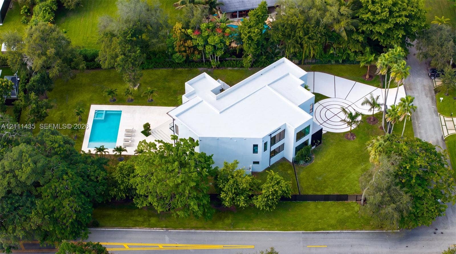 9530 SW 95th Court, Miami, FL 33176 Modern multi-level estate featuring a flat-roof architectural design, a private swimming pool with an integrated spa, expansive lawn, and a decorative concrete driveway with geometric detailing