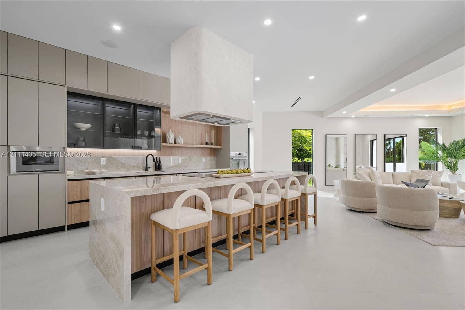 9530 SW 95th Court, Miami, FL 33176 Modern kitchen featuring matte-finish cabinetry, a waterfall-edge stone island, integrated oven and microwave, recessed lighting, and a custom plaster range hood