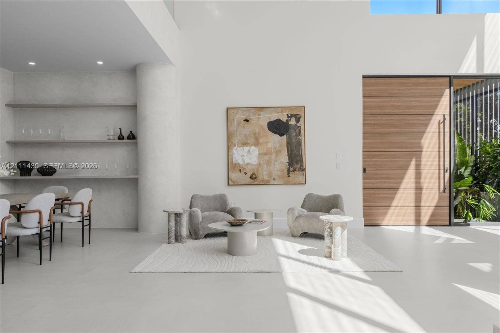 9530 SW 95th Court, Miami, FL 33176 Double-height ceiling with recessed lighting, integrated stone shelving, polished concrete flooring, oversized wood-finish front entry door, and floor-to-ceiling glass wall