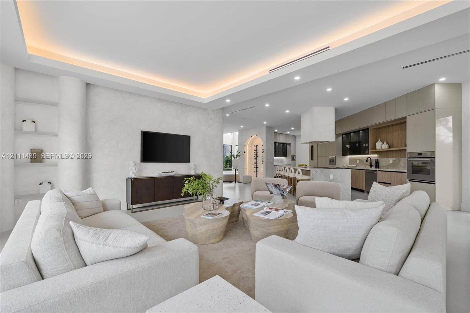 9530 SW 95th Court, Miami, FL 33176 Open-concept interior featuring a recessed tray ceiling with integrated cove lighting, textured wall finish, built-in display shelving, and custom cabinetry with wood-tone accents