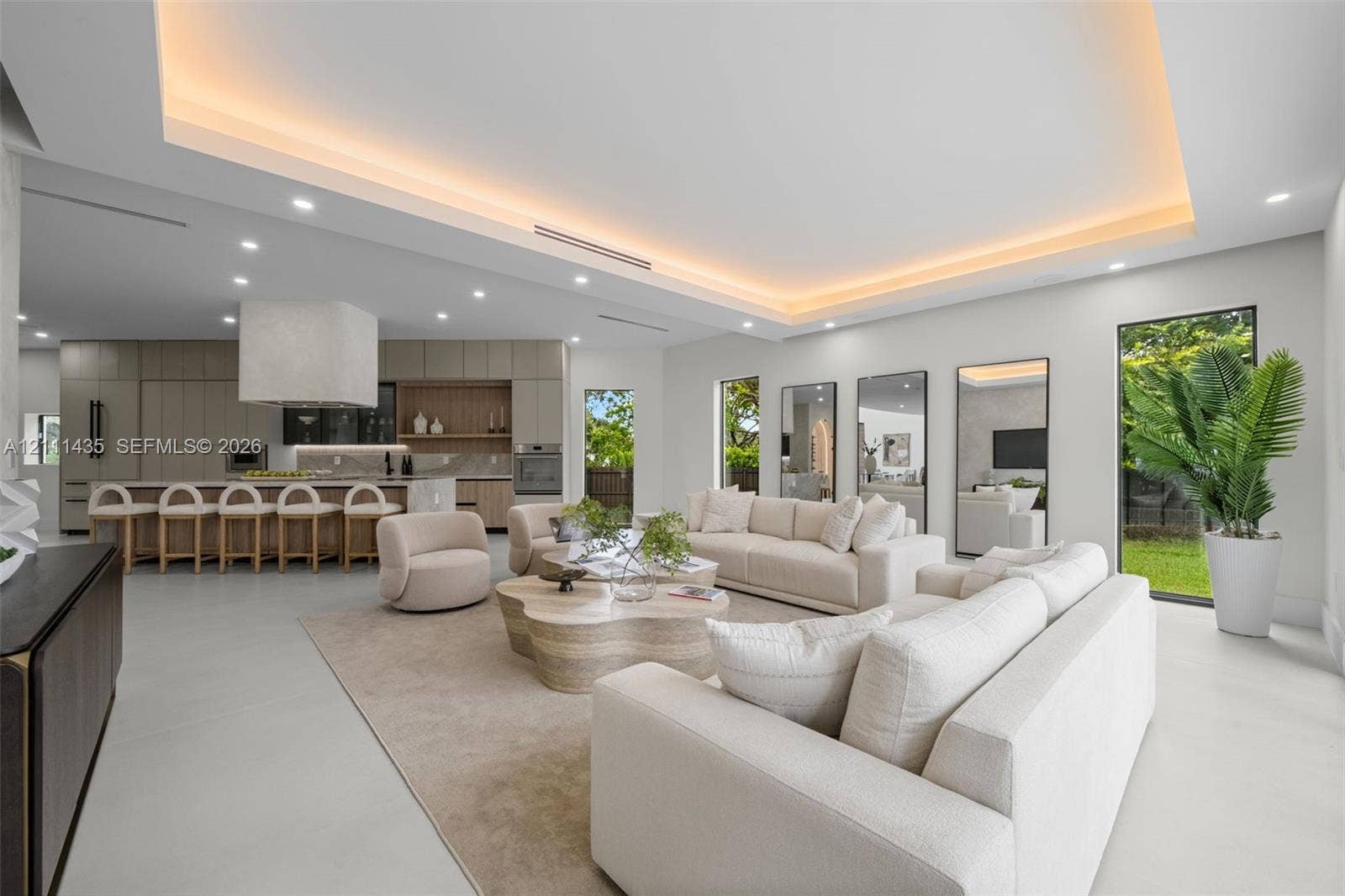 9530 SW 95th Court, Miami, FL 33176 Open-concept interior featuring a recessed tray ceiling with integrated cove lighting, polished concrete flooring, built-in floor-to-ceiling cabinetry, and full-height windows