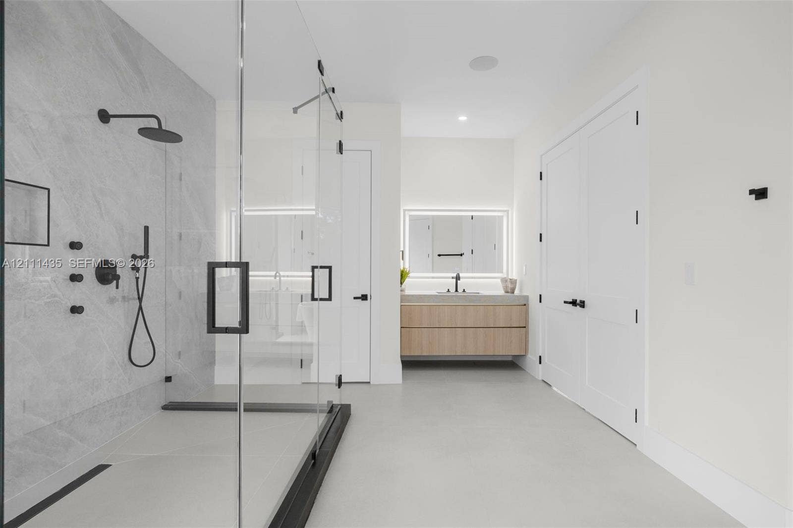 9530 SW 95th Court, Miami, FL 33176 Walk-in shower with frameless glass enclosure, rainfall shower head, and stone-tile surround, paired with a floating wood-finish vanity featuring an integrated LED-backlit mirror