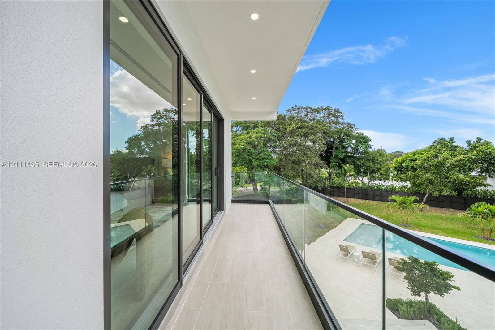 9530 SW 95th Court, Miami, FL 33176 Covered balcony featuring expansive sliding glass doors, frameless glass railings, recessed lighting, and tile flooring