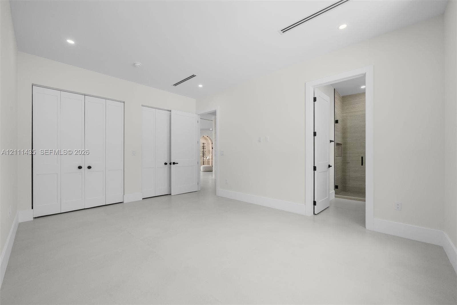 9530 SW 95th Court, Miami, FL 33176 Room featuring smooth flooring, recessed lighting, double-door closet cabinetry, and a doorway revealing a tiled shower enclosure