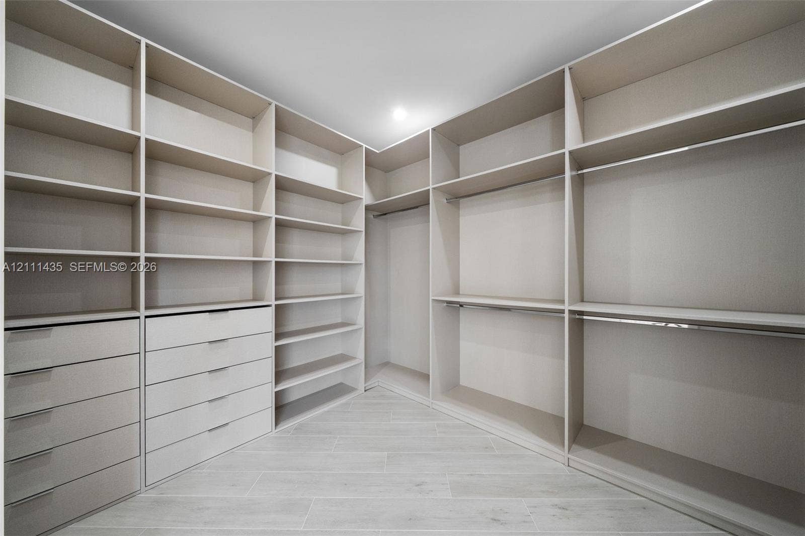 9530 SW 95th Court, Miami, FL 33176 Walk-in closet featuring extensive built-in shelving, integrated multi-drawer cabinetry, dual-level hanging rods, and light-toned tile flooring