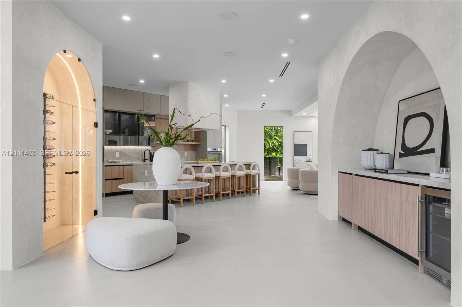 9530 SW 95th Court, Miami, FL 33176 Open-concept floor plan featuring arched architectural entryways, a climate-controlled glass wine cellar, custom light wood cabinetry, and recessed lighting