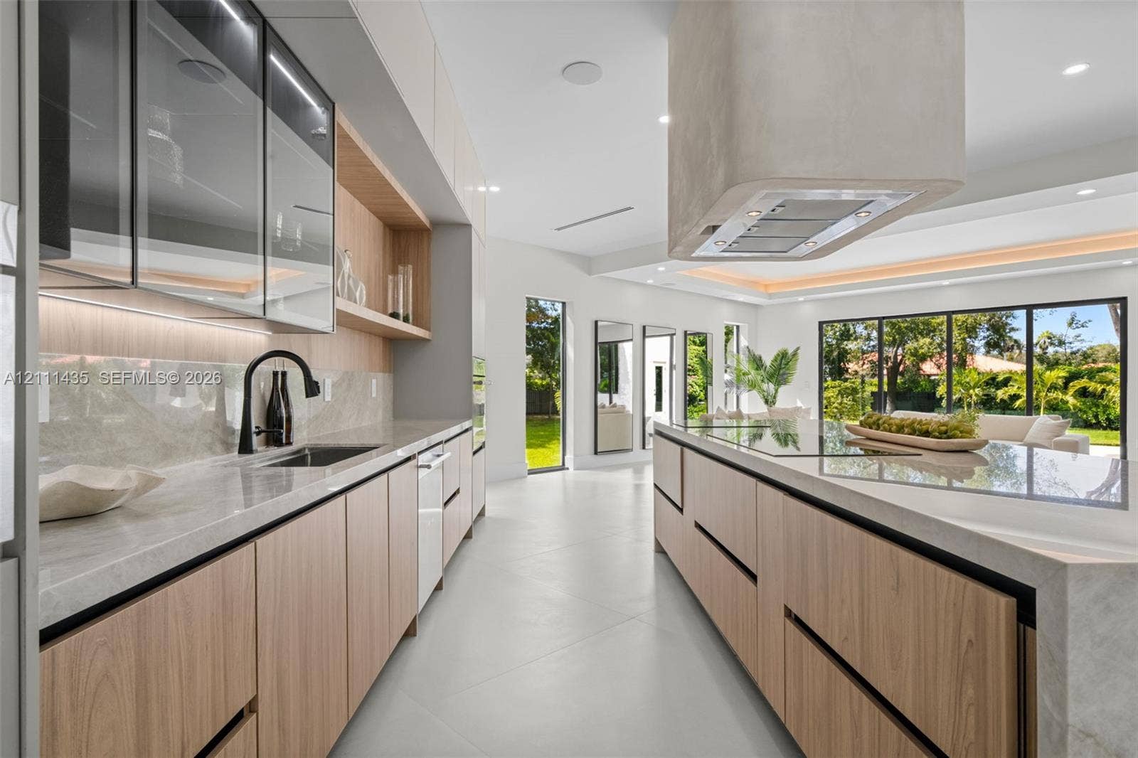 9530 SW 95th Court, Miami, FL 33176 Kitchen featuring light wood-finish cabinetry, stone countertops, integrated under-cabinet lighting, a contemporary ceiling-mounted range hood, and large-format tile flooring