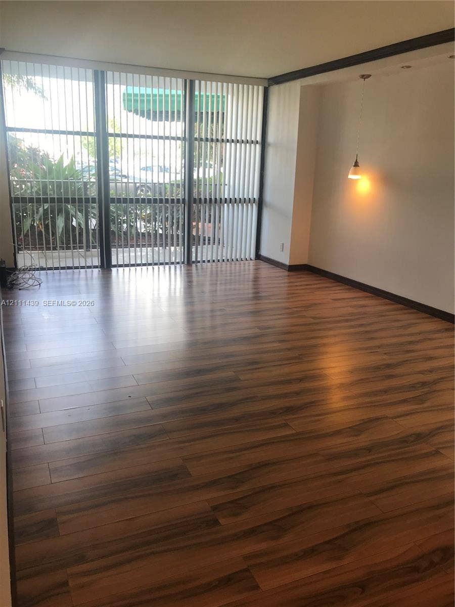 800 Parkview Drive, #102, Hallandale Beach, Hallandale Beach, FL 33009 Floor-to-ceiling windows with vertical blinds, wood-finish flooring, and a recessed ceiling feature with a pendant light fixture