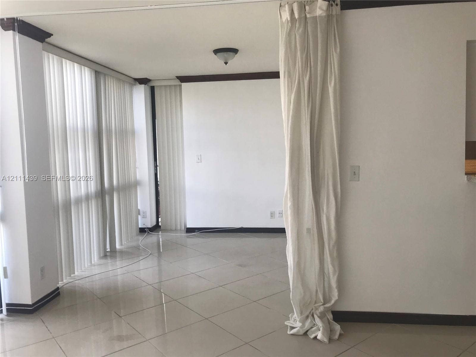 800 Parkview Drive, #102, Hallandale Beach, Hallandale Beach, FL 33009 Interior space featuring floor-to-ceiling vertical blinds, neutral tile flooring, and dark-toned crown molding