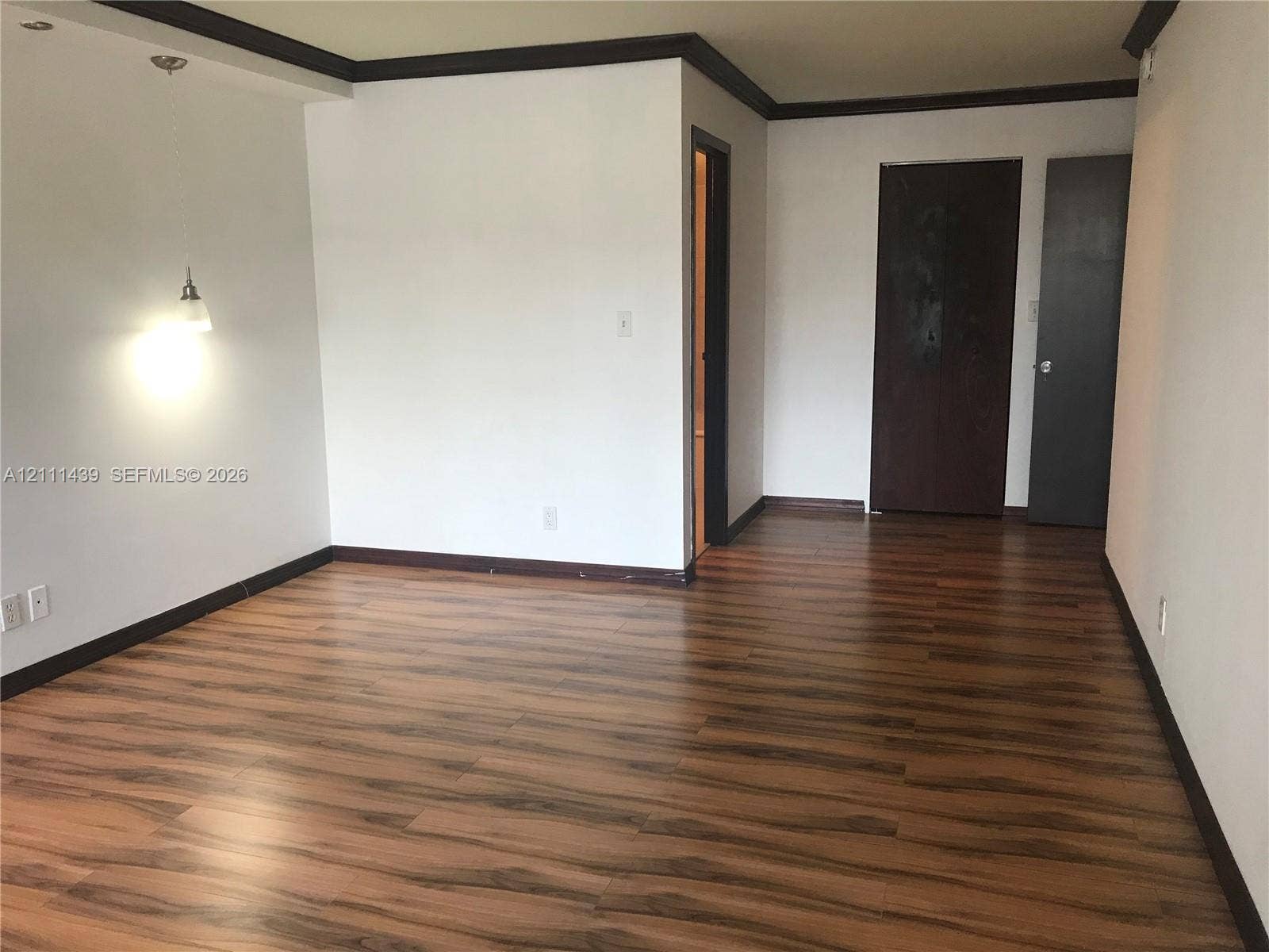 800 Parkview Drive, #102, Hallandale Beach, Hallandale Beach, FL 33009 Wood-finish flooring, dark-toned interior door trim, crown molding, and a suspended pendant light fixture