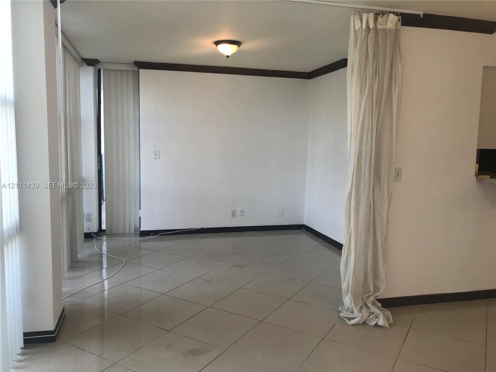 800 Parkview Drive, #102, Hallandale Beach, Hallandale Beach, FL 33009 Interior space featuring large-format ceramic tile flooring, neutral wall tones, contrasting dark crown molding, and floor-to-ceiling vertical window blinds