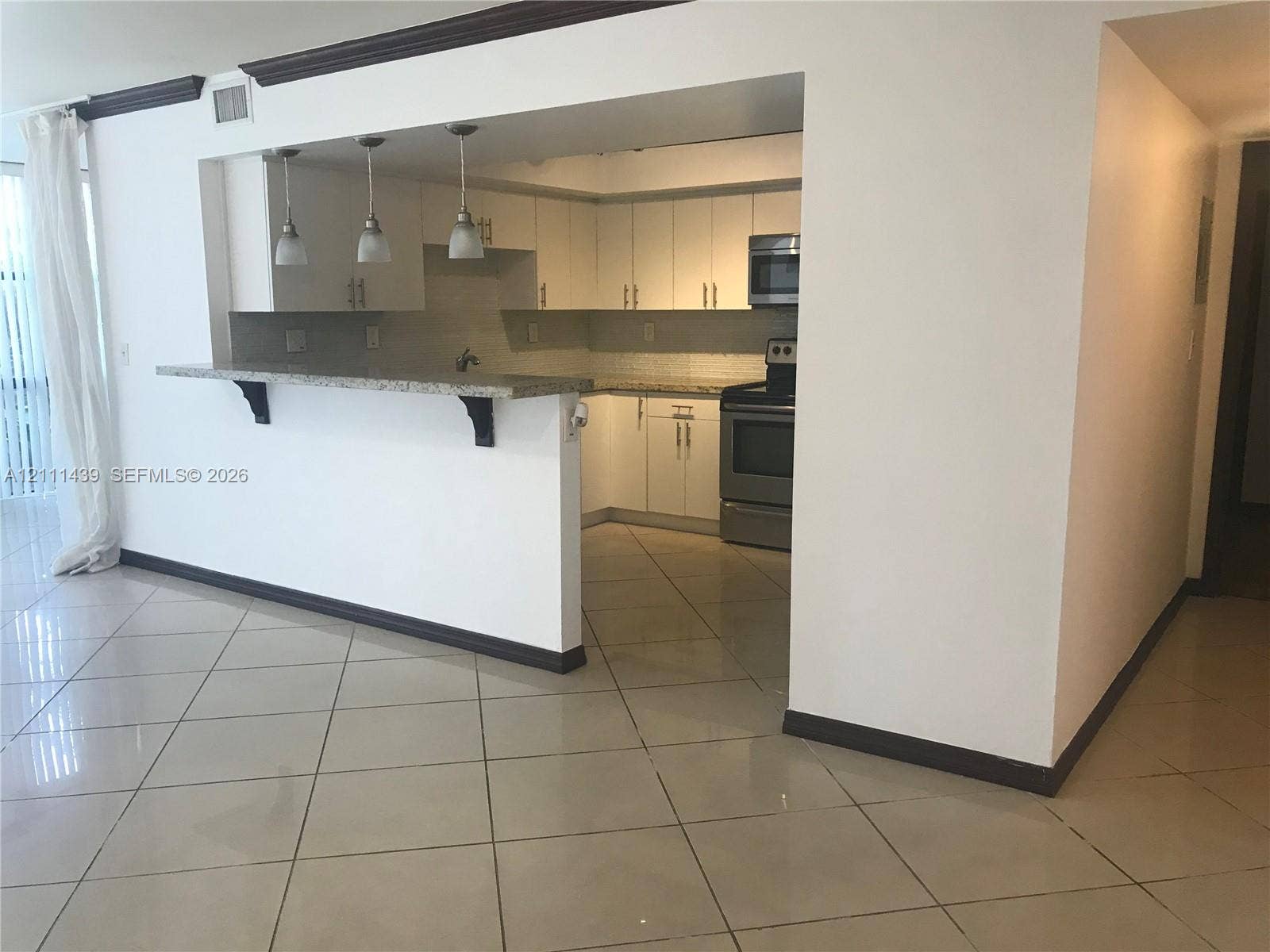 800 Parkview Drive, #102, Hallandale Beach, Hallandale Beach, FL 33009 Kitchen featuring white cabinetry, stone-finish countertops, stainless steel appliance suite, tile flooring, and a breakfast bar with three pendant lights