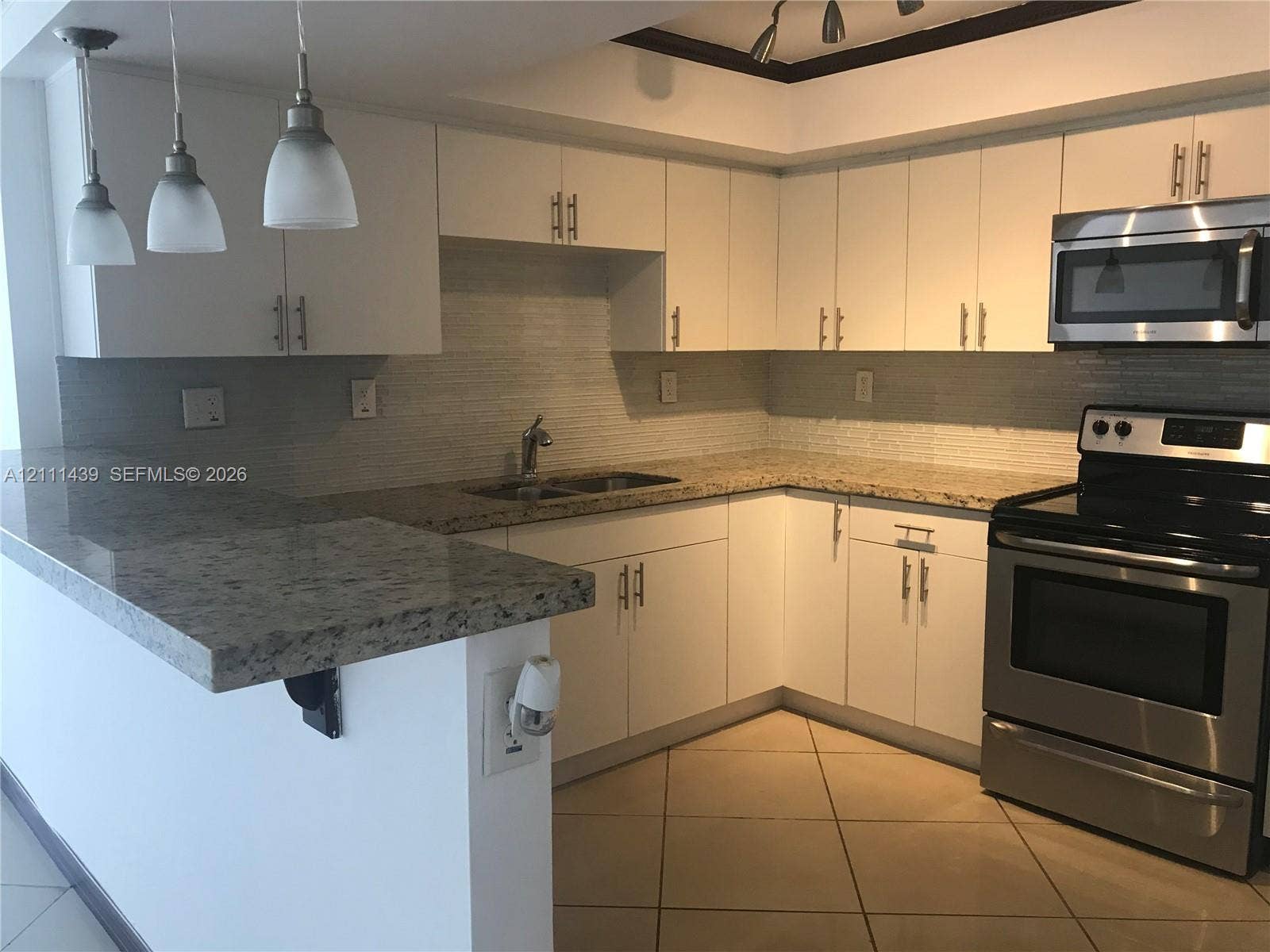 800 Parkview Drive, #102, Hallandale Beach, Hallandale Beach, FL 33009 Kitchen featuring white cabinetry with brushed metal hardware, stone-surface countertops, stainless steel appliances, a tiled backsplash, and three pendant lights