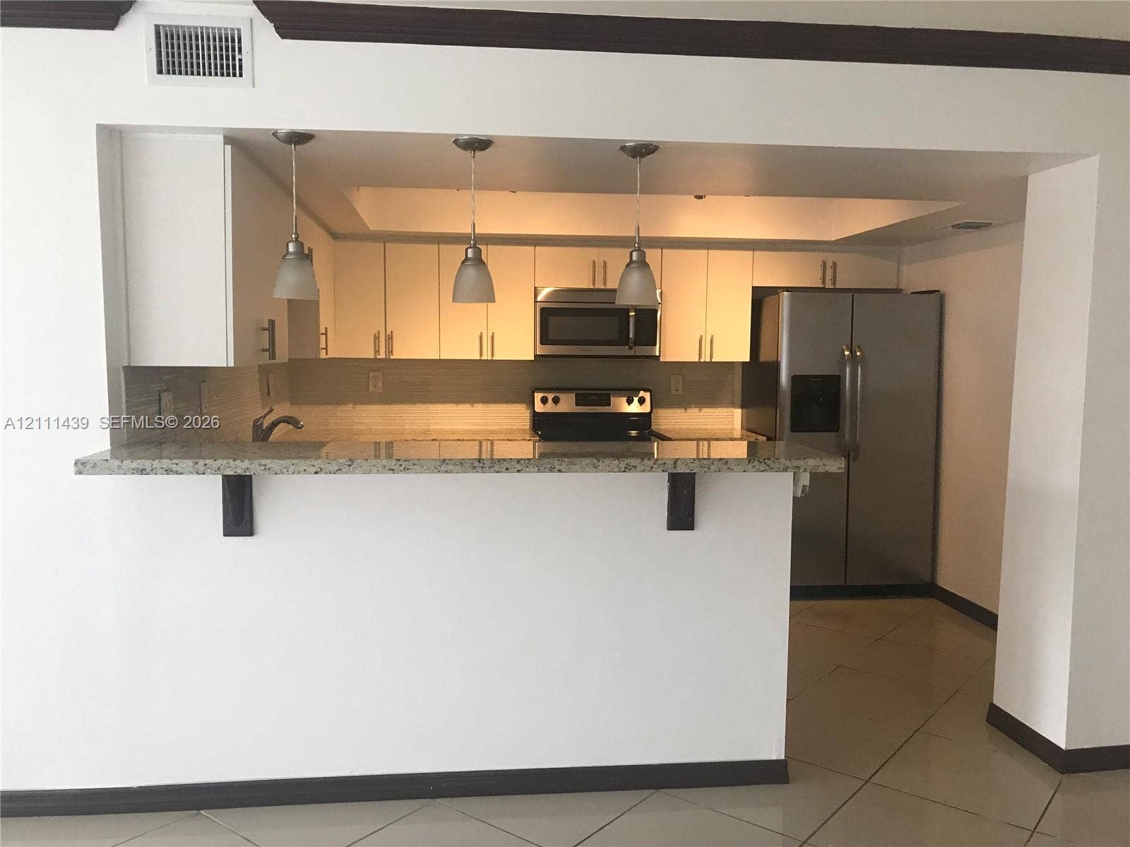 800 Parkview Drive, #102, Hallandale Beach, Hallandale Beach, FL 33009 Kitchen featuring a pass-through breakfast bar, stone-finish countertops, stainless steel appliances, white cabinetry, and three pendant lights
