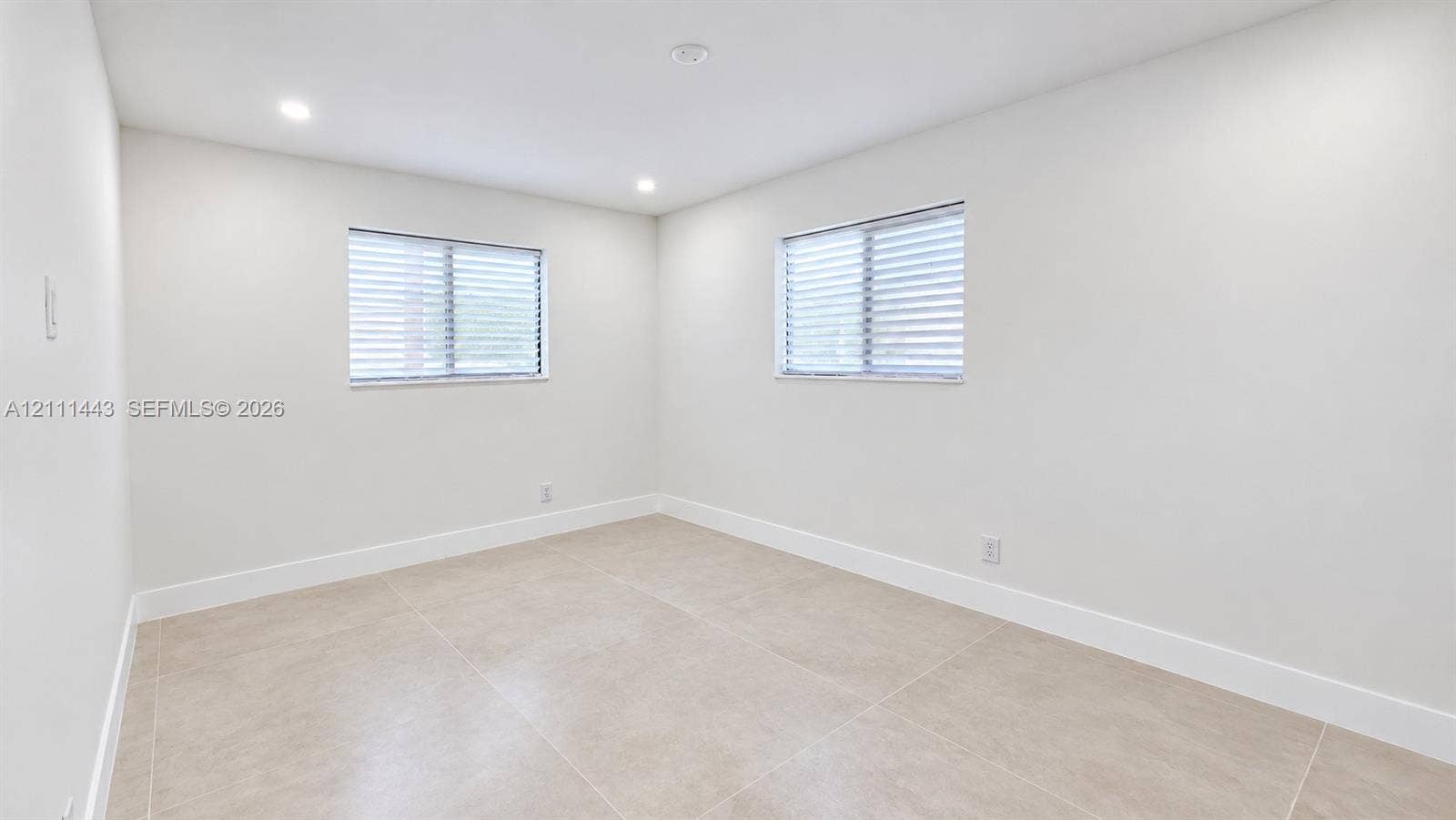 Neutral-toned tile flooring, two horizontal windows featuring integrated blinds, and recessed ceiling lighting