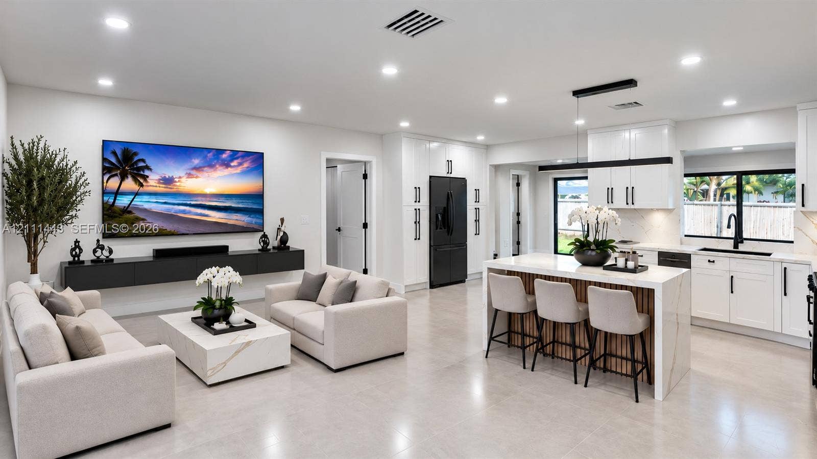 Digitally Staged- Open-concept living space featuring high-gloss white cabinetry, a kitchen island with stone-finish waterfall countertops, matte black hardware, tile flooring, and a wall-mounted floating media console