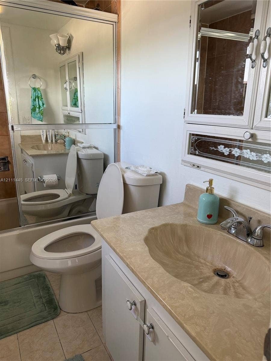 8255 Abbott Avenue, #402, Miami Beach, Miami Beach, FL 33141 Vanity featuring an integrated molded sink, stone-finish countertop, and chrome dual-handle faucet, complemented by a large wall-mounted mirror and a built-in recessed medicine cabinet with decorative glass detailing