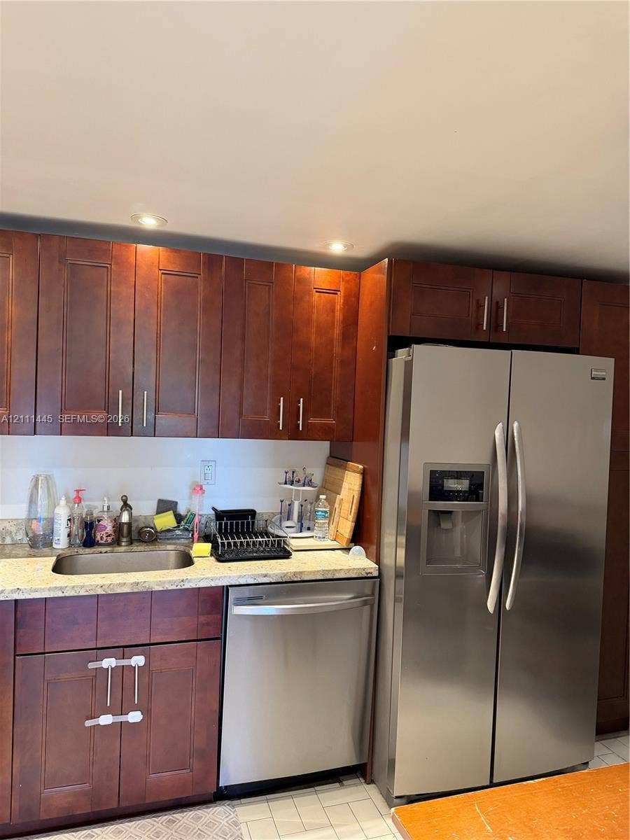 8255 Abbott Avenue, #402, Miami Beach, Miami Beach, FL 33141 Kitchen area featuring dark-stained wood cabinetry, stone-finish countertops, stainless steel side-by-side refrigerator, under-mount stainless steel sink, and stainless steel dishwasher