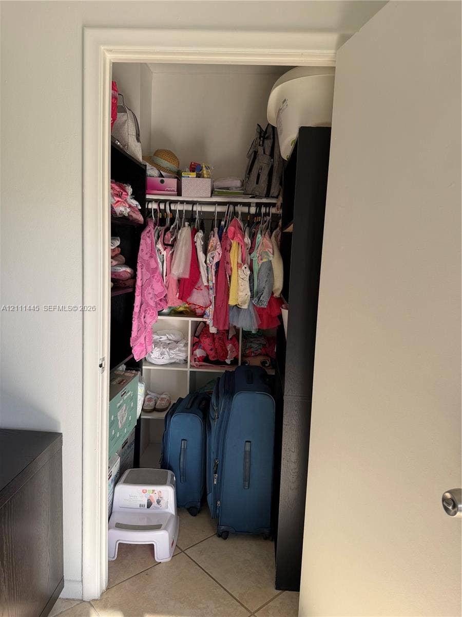 8255 Abbott Avenue, #402, Miami Beach, Miami Beach, FL 33141 Reach-in closet featuring white wire shelving, a multi-cube storage organizer, and diagonal tile flooring