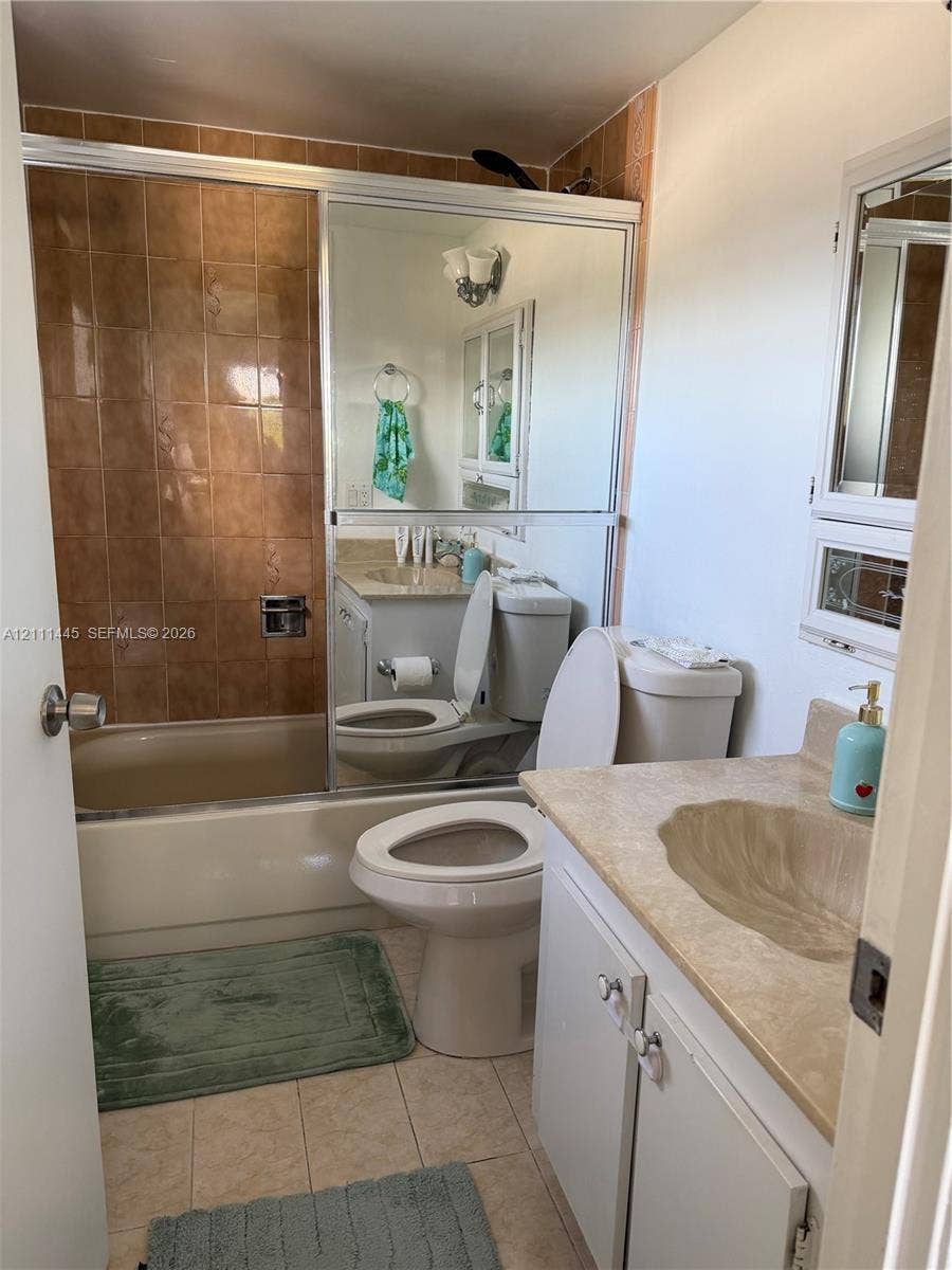 8255 Abbott Avenue, #402, Miami Beach, Miami Beach, FL 33141 Bathroom featuring a shower-tub combination with tiled surround, sliding glass door, vanity with integrated sink, and medicine cabinet