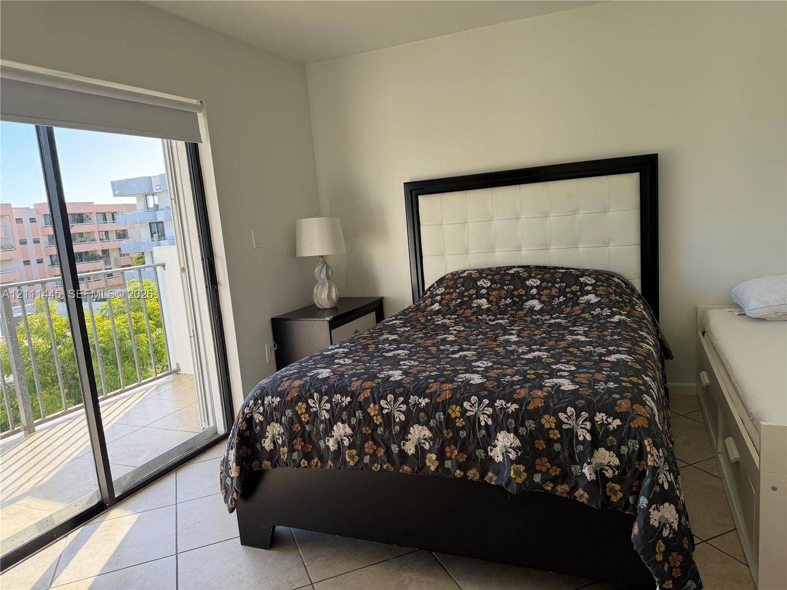 8255 Abbott Avenue, #402, Miami Beach, Miami Beach, FL 33141 Sliding glass door opening to a private balcony with metal railing, neutral tile flooring, and light-toned wall finishes