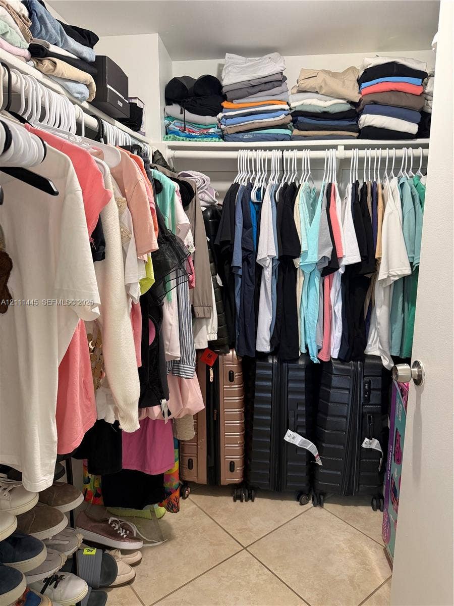 8255 Abbott Avenue, #402, Miami Beach, Miami Beach, FL 33141 Reach-in closet featuring multi-level hanging rods, upper shelving, and tile flooring