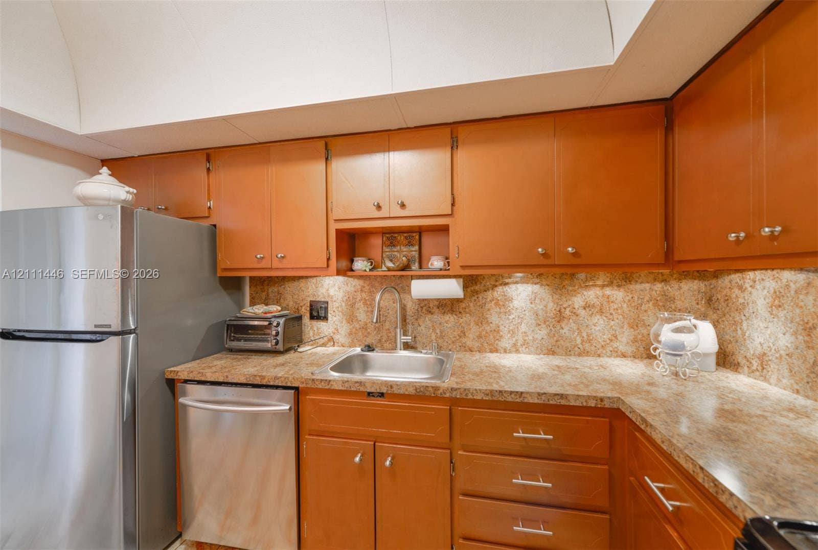 1965 S Ocean Drive, #15M, Hallandale Beach, Hallandale Beach, FL 33009 Kitchen featuring wood cabinetry, stone-finish countertops, stainless steel appliances, a drop-in stainless steel sink, and a stone-finish backsplash