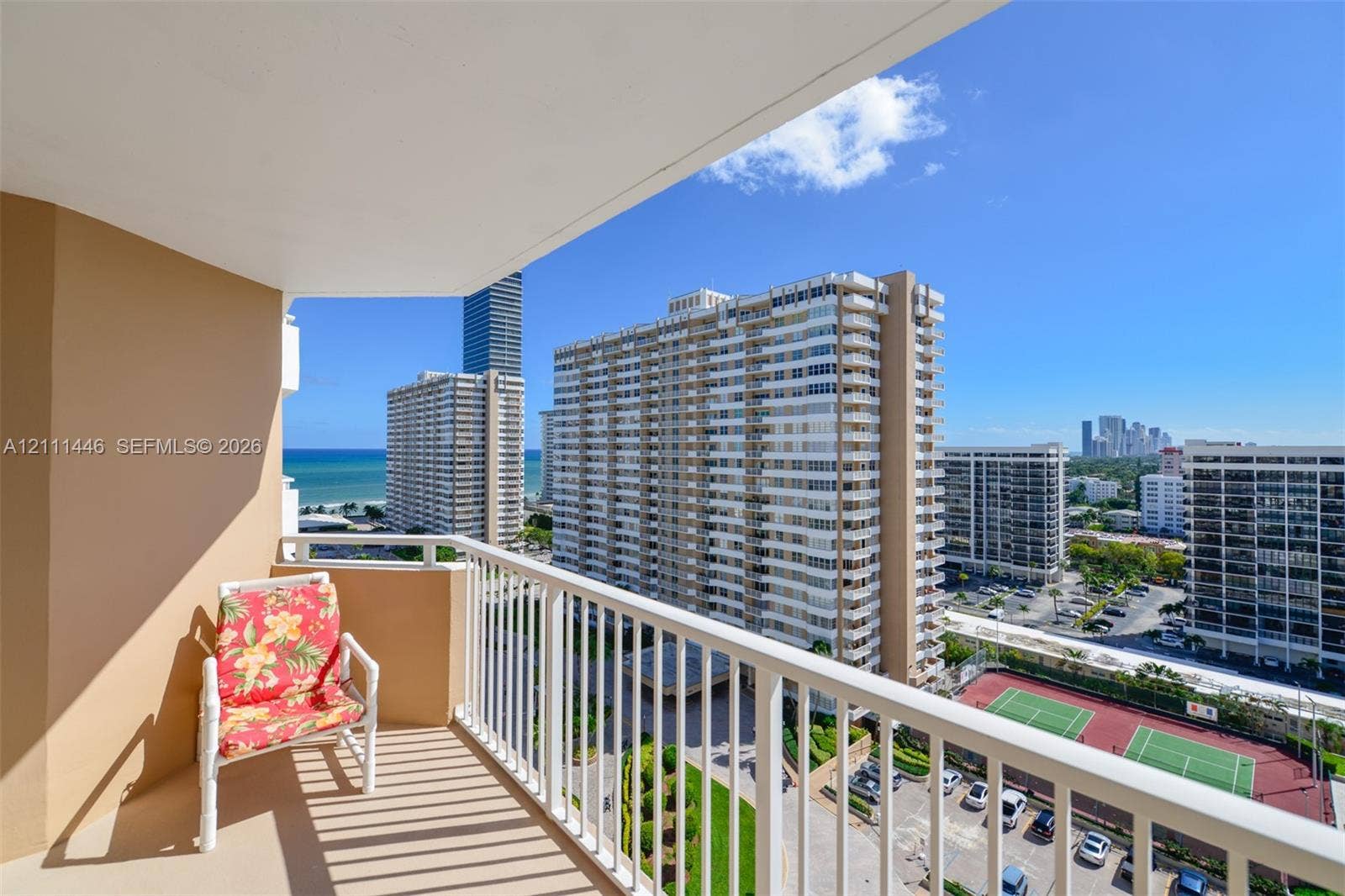 1965 S Ocean Drive, #15M, Hallandale Beach, Hallandale Beach, FL 33009 Covered balcony featuring white vertical railings and concrete flooring, overlooking an outdoor tennis court