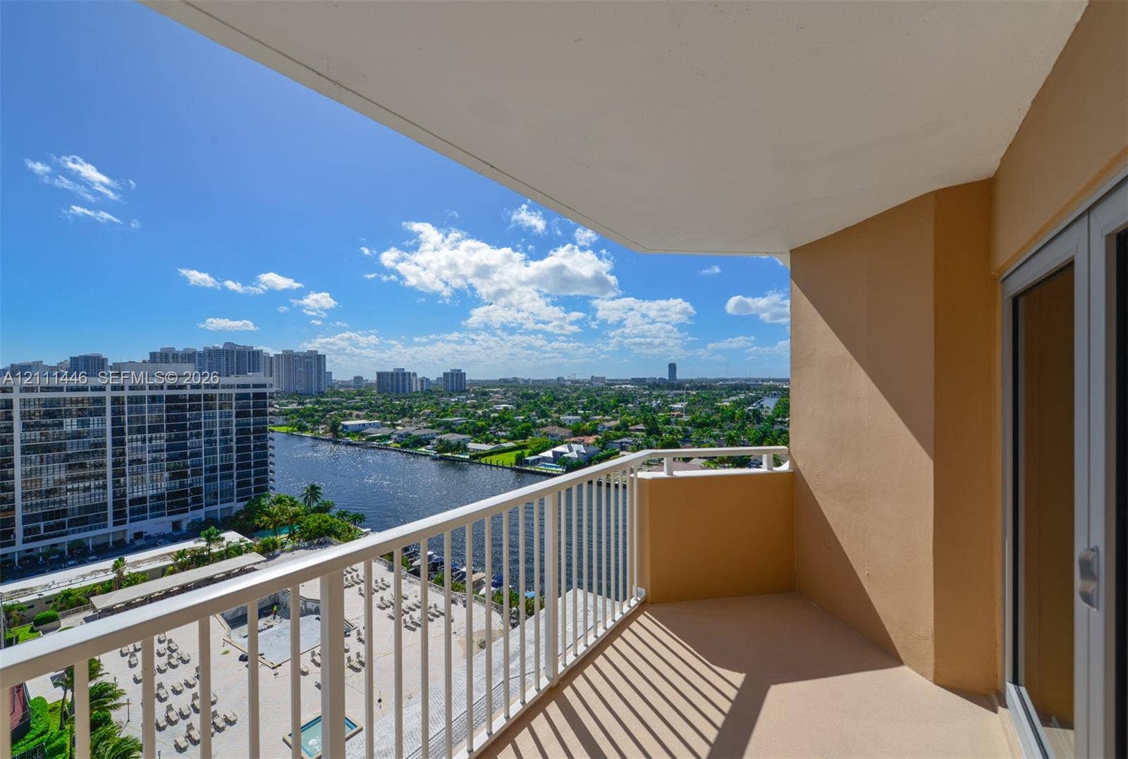 1965 S Ocean Drive, #15M, Hallandale Beach, Hallandale Beach, FL 33009 Covered balcony featuring a white metal railing and concrete flooring, overlooking the waterway and urban landscape