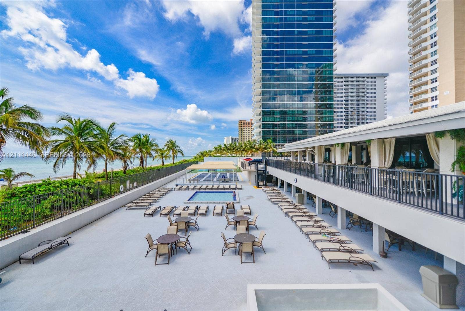 1965 S Ocean Drive, #15M, Hallandale Beach, Hallandale Beach, FL 33009 Expansive sun deck featuring a swimming pool, integrated metal railing, oceanfront scenery, and tall palm tree landscaping