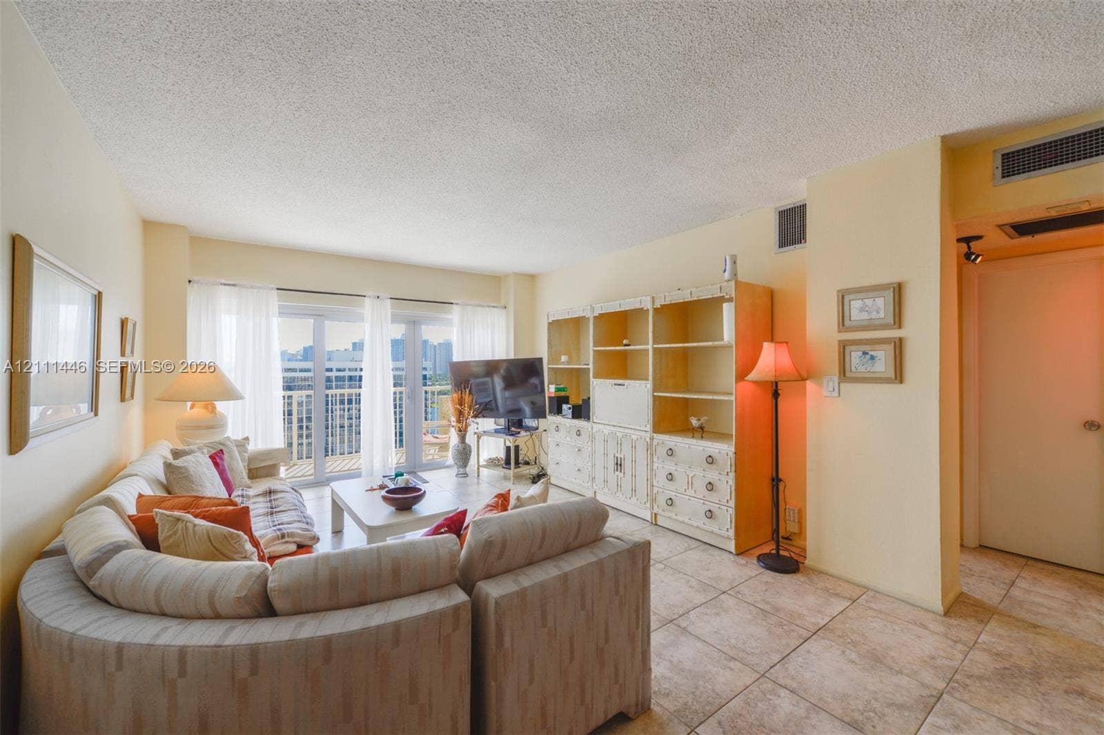 1965 S Ocean Drive, #15M, Hallandale Beach, Hallandale Beach, FL 33009 Living area featuring large-format ceramic tile flooring, built-in floor-to-ceiling cabinetry, and expansive glass sliding doors providing exterior access