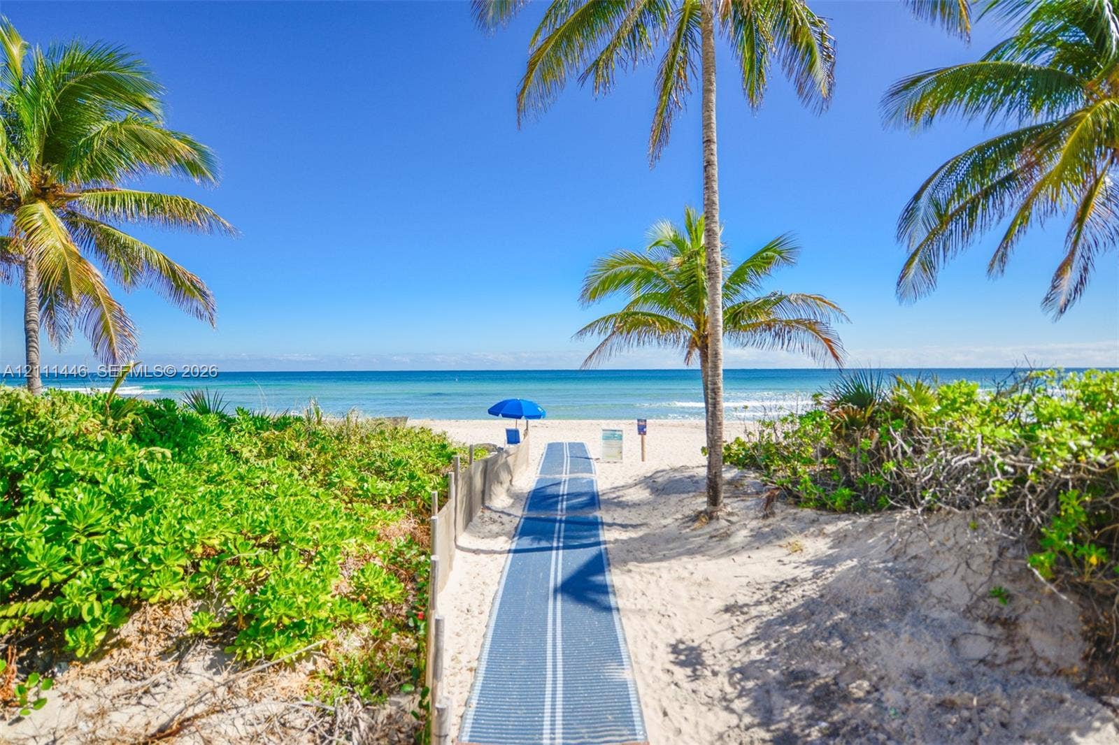 1965 S Ocean Drive, #15M, Hallandale Beach, Hallandale Beach, FL 33009 Private sandy beach access featuring a synthetic pathway, native coastal vegetation, and palm trees
