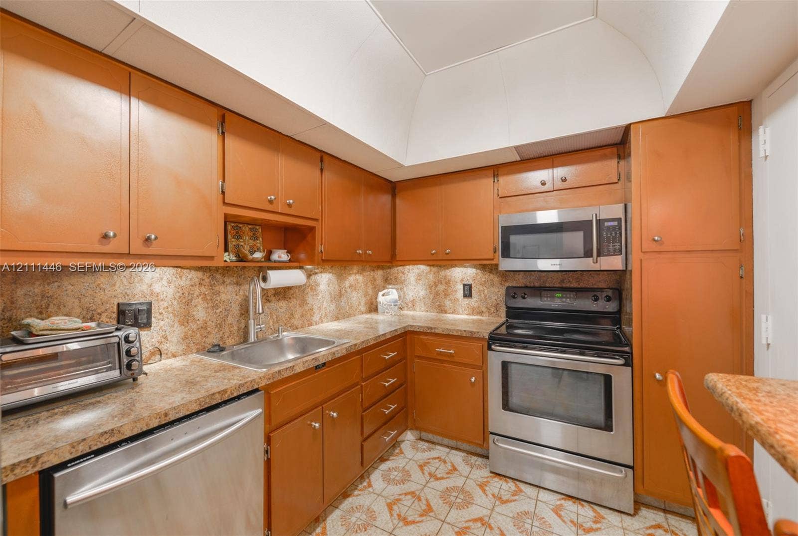 1965 S Ocean Drive, #15M, Hallandale Beach, Hallandale Beach, FL 33009 Kitchen featuring wood cabinetry, stainless steel appliances, patterned flooring, recessed lighting, and a vaulted ceiling
