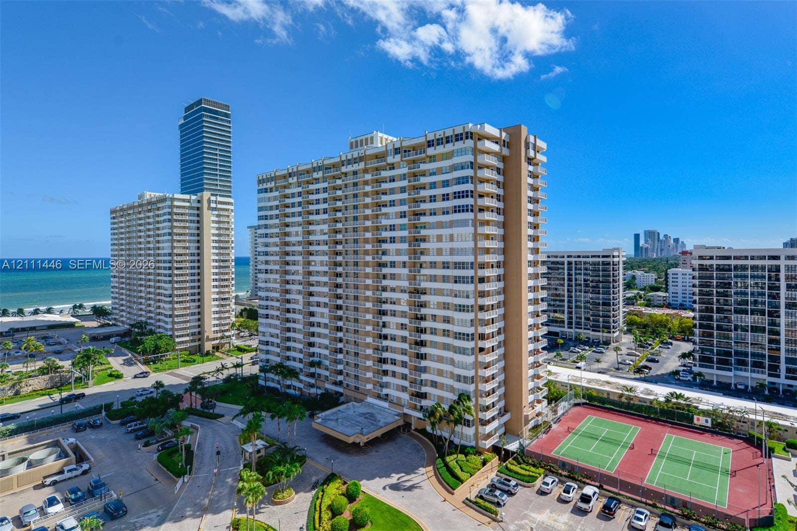 1965 S Ocean Drive, #15M, Hallandale Beach, Hallandale Beach, FL 33009 High-rise residential building featuring multiple private balconies, a covered porte-cochre entry, and dual outdoor tennis courts