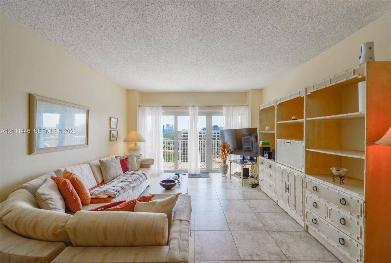 1965 S Ocean Drive, #15M, Hallandale Beach, Hallandale Beach, FL 33009 Living area featuring large-format neutral floor tile, built-in floor-to-ceiling cabinetry, and glass paneled doors providing exterior access